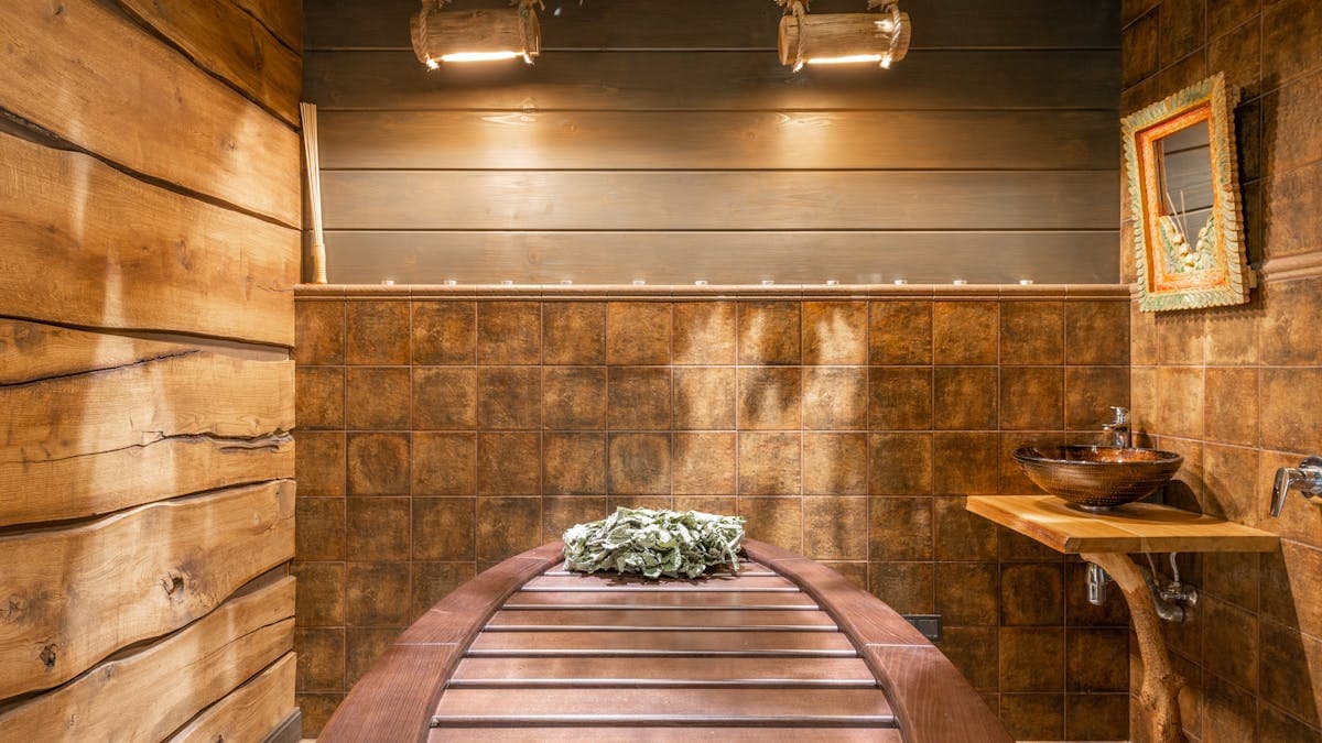 Rustic traditional sauna room with natural wood walls and birch venik whisk